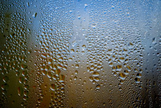 Condensation with beaded moisture droplets on the outside of a cold glass or bottle in a close up full frame background texture