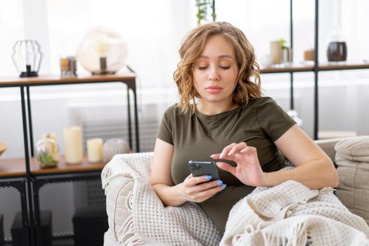 Pregnant woman lying on the couch holding smartphone in hand Relax enjoy atmosphere