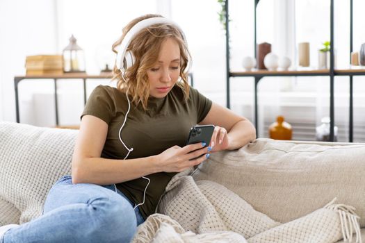 Pregnant woman listen music headphones lying on the couch holding smartphone in hand Relax enjoy atmospere