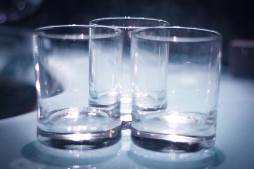 Three empty crystal glasses on dark background. No people