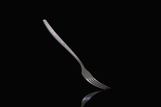 Old steel fork on black background. Metal fork on dark background close up.