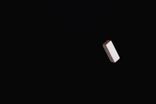 One levitating chocolate wafer on a black background