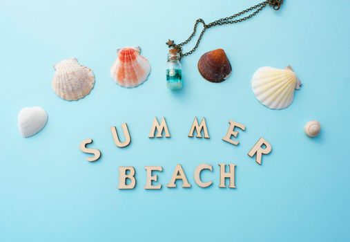 Summer beach wooden inscription. White shells and bottle decoration on light blue background.