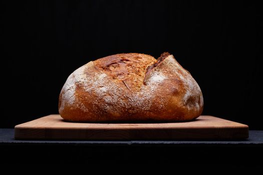 Artisan sourdough bread. Freshly baked round loaf of sourdough bread on black background.