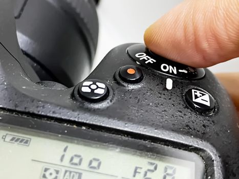 finger pressing the shutter button of a camera to take a photo. Buttons and settings of a digital reflex camera.