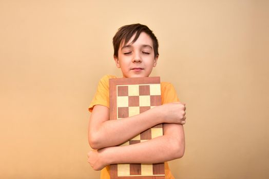 boy holds a chessboard in his hands and dreams and thinks about the game.