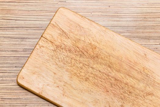 Old chopping board on wooden background top view.