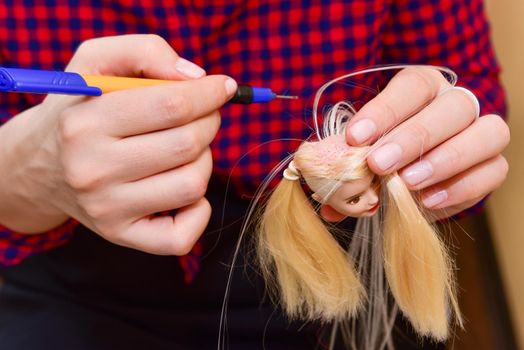 female hands and homemade tool, how to make a hairstyle for a doll, hobby concept.