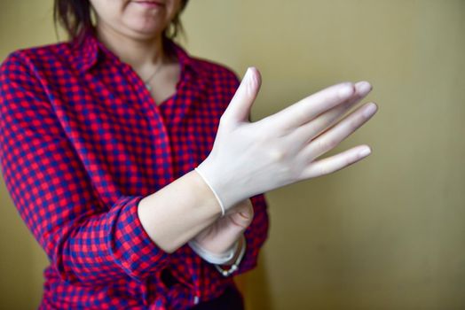 Personal protective equipment vinyl disposable gloves, woman puts her hands in gloves.