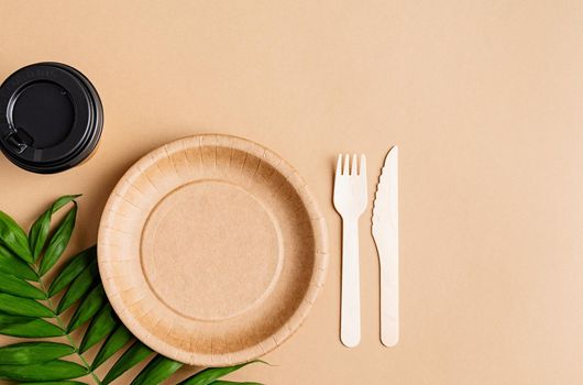 Knolling concept. Eco friendly zero waste disposable tableware top view flat lay on brown background. Craft paper plate, cup, fork and knife. Copy space