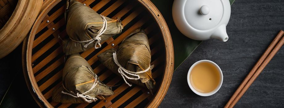 Zongzi rice dumpling top view for Chinese traditional Dragon Boat Festival (Duanwu Festival) over dark black slate background.