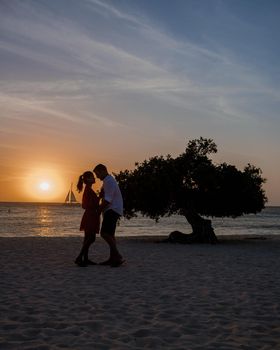 Sunset at Eagle Beach Aruba, Divi Dive Trees on the shoreline of Eagle Beach in Aruba, couple man and woman watchin sunset on the beach of Aruba