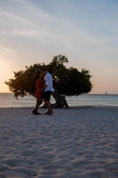 Sunset at Eagle Beach Aruba, Divi Dive Trees on the shoreline of Eagle Beach in Aruba, couple man and woman watchin sunset on the beach of Aruba