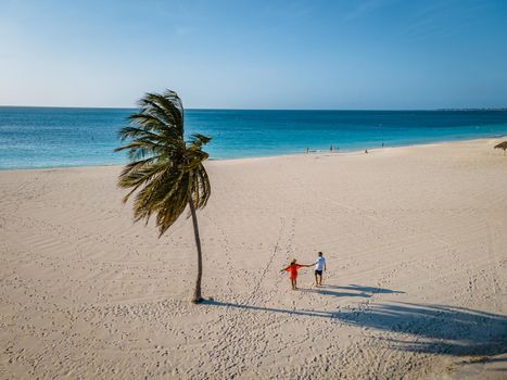 Eagle Beach Aruba, Palm Trees on the shoreline of Eagle Beach in Aruba, couple man, and woman on the beach of Aruba