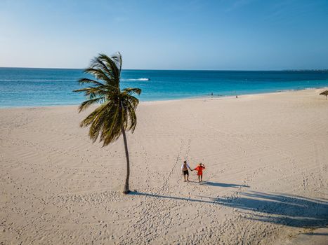 Eagle Beach Aruba, Palm Trees on the shoreline of Eagle Beach in Aruba, couple man, and woman on the beach of Aruba