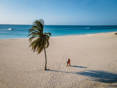 Eagle Beach Aruba, Palm Trees on the shoreline of Eagle Beach in Aruba, couple man, and woman on the beach of Aruba