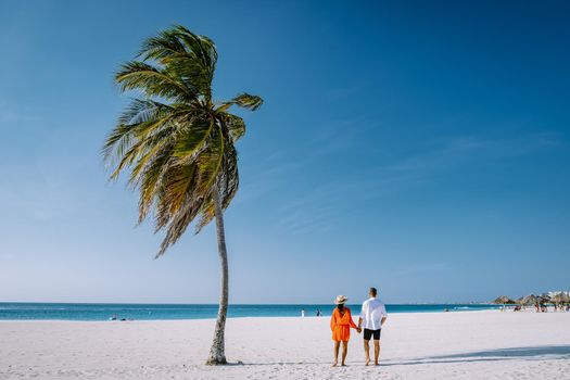 Eagle Beach Aruba, Palm Trees on the shoreline of Eagle Beach in Aruba, couple man, and woman on the beach of Aruba