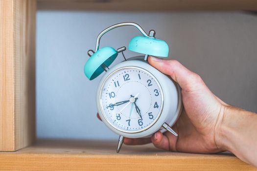 Retro styled white alarm clock in the wooden bookshelf