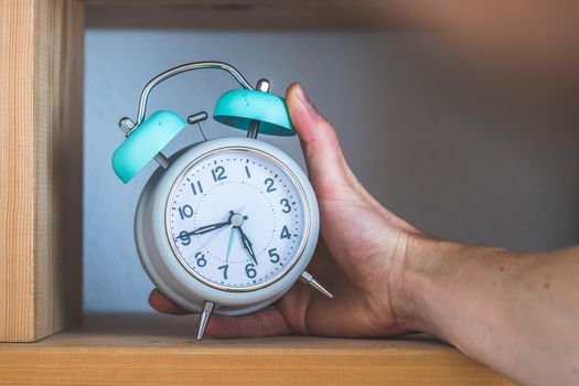 Retro styled white alarm clock in the wooden bookshelf