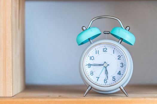 Retro styled white alarm clock in the wooden bookshelf
