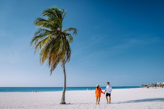 Eagle Beach Aruba, Palm Trees on the shoreline of Eagle Beach in Aruba, couple man, and woman on the beach of Aruba