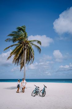 Eagle Beach Aruba, Palm Trees on the shoreline of Eagle Beach in Aruba, couple man, and woman on the beach of Aruba, couple with bycicle