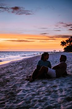 Sunset at Eagle Beach Aruba, Divi Dive Trees on the shoreline of Eagle Beach in Aruba, couple man and woman watchin sunset on the beach of Aruba