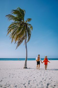 Eagle Beach Aruba, Palm Trees on the shoreline of Eagle Beach in Aruba, couple man, and woman on the beach of Aruba