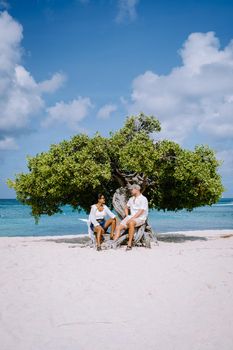 Eagle Beach Aruba, Divi Dive Trees on the shoreline of Eagle Beach in Aruba, couple man and woman watchin sunset on the beach of Aruba