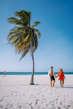 Eagle Beach Aruba, Palm Trees on the shoreline of Eagle Beach in Aruba, couple man, and woman on the beach of Aruba