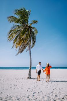 Eagle Beach Aruba, Palm Trees on the shoreline of Eagle Beach in Aruba, couple man, and woman on the beach of Aruba