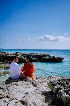 Boca Catalina Beach Aruba, rocks and cliffs and blue ocean Aruba, couple men and woman sitting on a rock watching together