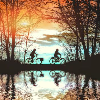 Silhouette man riding bike at sunset