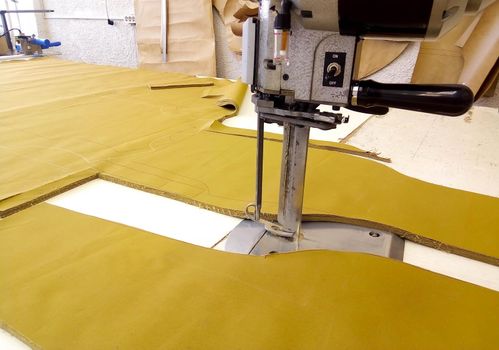 Tool cutter in the garment industry. Cutting parts of clothing with an electric knife made of multi-layer fabric.