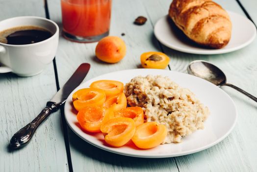 Breakfast set. Porridge with sliced apricot, cup of coffee, glass of grapefruit juice and croissant