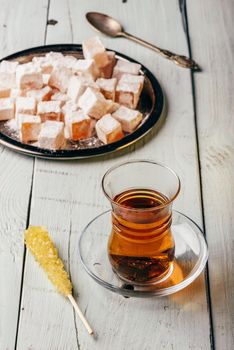 Tea in arabic glass with turkish delight Rahat Lokum over wooden surface