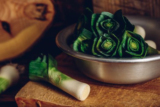 Fresh green leek in grey bowl over wooden surface