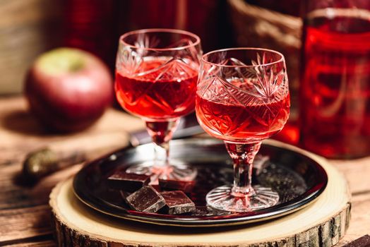 Glass of red liquor with chocolate bars on metal tray