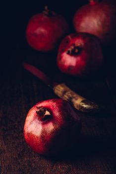 Fresh pomegranate fruit on wooden surface. Knife with some fruits on background. Toned