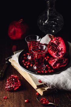 Homemade pomegranate liqueur with fresh fruit on metal tray