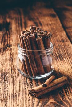 Cinnamon sticks in a glass jar over rustic wooden surface