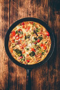 Vegetable frittata with broccoli, red bell pepper and red onion in cast iron pan. Top view