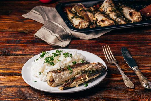 Baked hake carcasses with rice on white plate