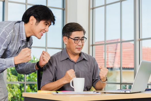 Asian senior and young business man people excited celebrating corporate victory together in office. Happy old and junior two businessmen video call conference on laptop computer success win triumph