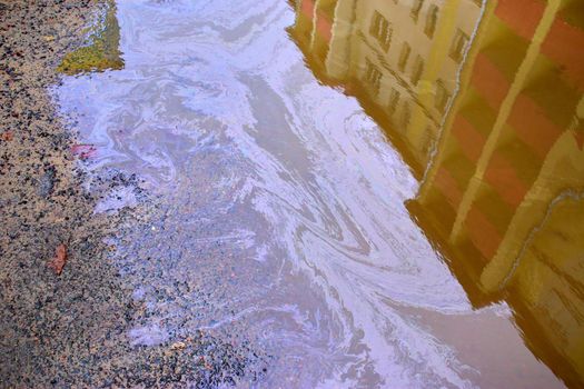 Beautiful abstract colorful background, stains of motor oil in a puddle with reflection of a building in blur, marbling texture