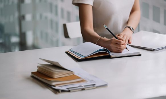 Close up of a woman writer hand writing in a notebook at home.