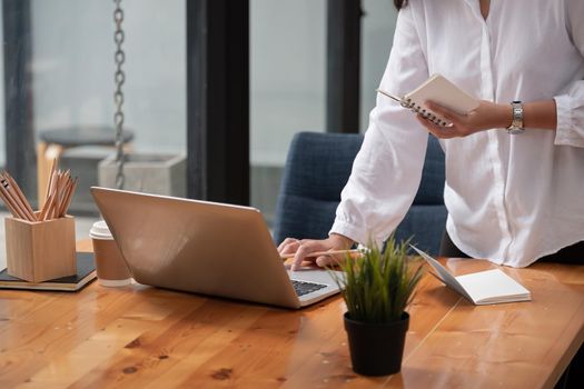 Cropped photo of woman writing making list taking notes in notepad working or learning on laptop indoors- educational course or training, seminar, education online concept