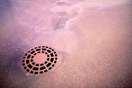 Oil slick on the asphalt road background drains into the storm drain.Water pollution environmental problems