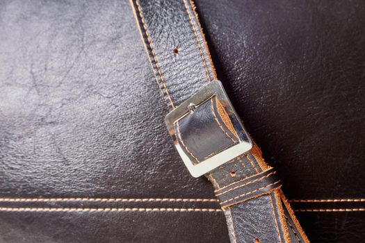 Fashionable black men's bag made of genuine leather close-up. Details of leather bag, belt, metal buckle, clasp. Selective focus