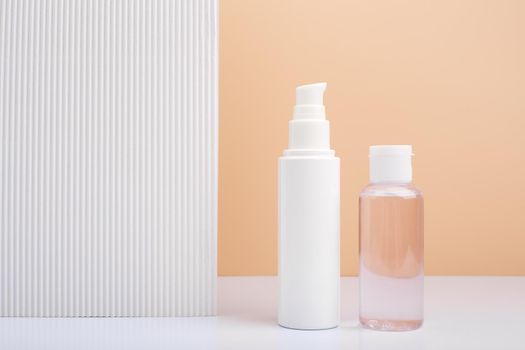Face cream and skin lotion next to white cardboard piece of paper against beige background with copy space. Concept of beauty products and cosmetics with natural organic ingredients